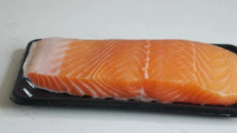 Salmon fillet portion on black plastic supermarket tray Vidéo 330447469