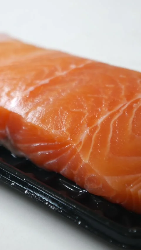 Salmon fillet portion on black plastic supermarket tray Видео 330447494