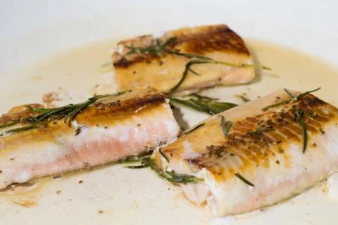 Salmon fillets getting cooked on a pan with rosemary Stock Photos
