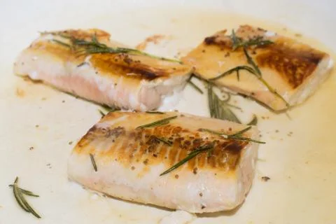 Salmon fillets getting cooked on a pan with rosemary Stock Photos