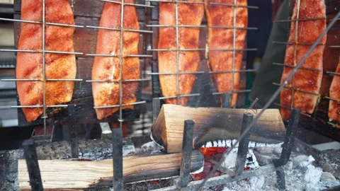 Salmon fillets grilling vertically over an open fire with aromatic branches Video stock 326124673