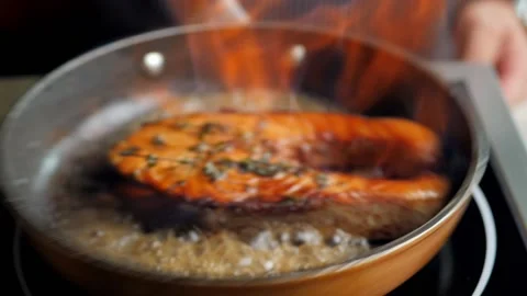 Salmon is fried in a pan by the chef. fire from a frying pan when frying fish. Stock Footage 158242448
