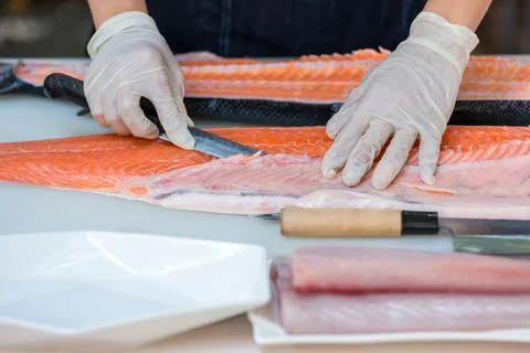 The salmon is in the hands of the experienced chef. Stock Photos