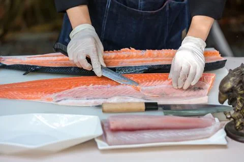 The salmon is in the hands of the experienced chef. Stock Photos