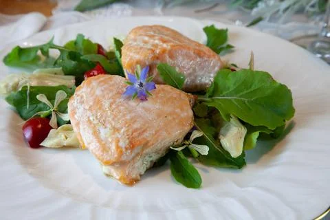 Salmon hearts on a spring green salad served on fine China plates and cryst.. Stock Photos
