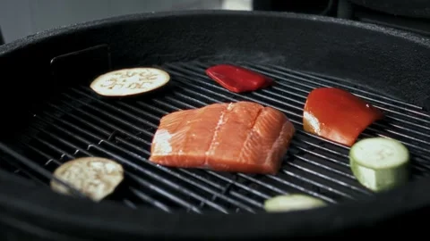 Salmon or trout steak is carefully placed on a blazing grill grate for frying Stock-Footage 314577208