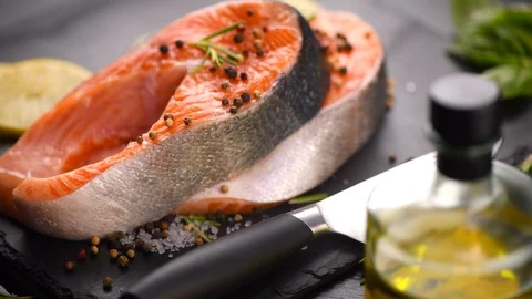 Salmon. Raw trout fish steak with herbs and lemon rotated on slate. Cooking Stock Footage