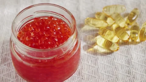Salmon red caviar close up and capsules of omega 3 fish oil. Delicious gourmet Stock Footage 301606462