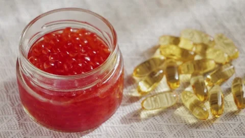 Salmon red caviar close up and capsules of omega 3 fish oil. Delicious gourmet Stock Footage 309089701