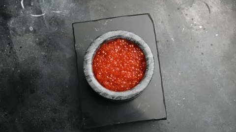 Salmon roe served in a stone bowl on a slate platter with a dark background Stock Footage 305228140