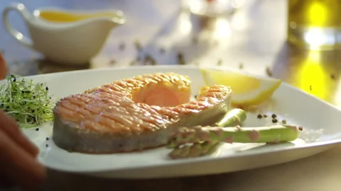 Salmon  steak and vegetable. Bottle of Olive oil pouring on salmon fish Stock Footage 132973074