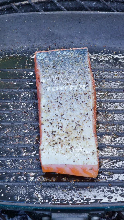 Salmon steak being cooked in a cast iron pan over coals. Slow motion footage Video stock 315268538