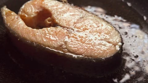 Salmon steak is cooked in a frying pan in close-up Stock Footage 277968882