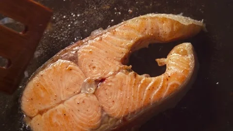 Salmon steak is cooked in a frying pan in close-up Stock Footage 277969005