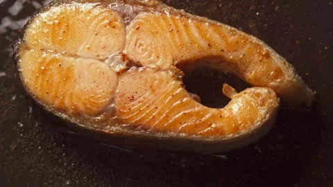 Salmon steak is cooked in a frying pan in close-up Stock Footage 277969073