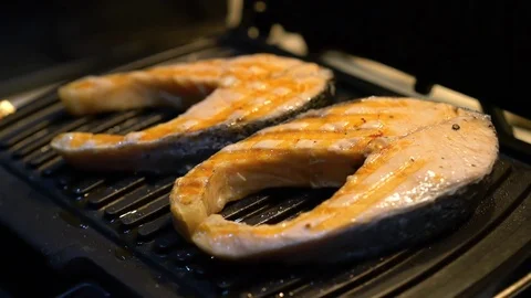 Salmon steak is fried on a grill Video stock 82973466
