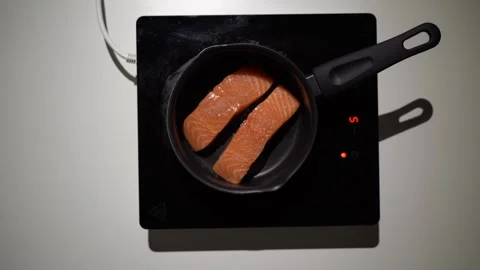 Salmon steak frying on small pan on small Induction Cooktop. Stock Footage 256932090
