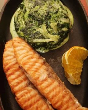 Salmon steak served with spinach Stock Photos