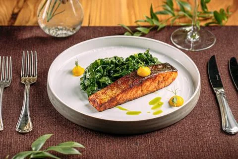 Salmon steak with spinach on served table Stock Photos