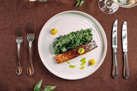 Salmon steak with spinach on served table Stock Photos
