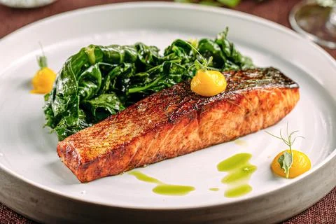 Salmon steak with spinach on served table Stock Photos
