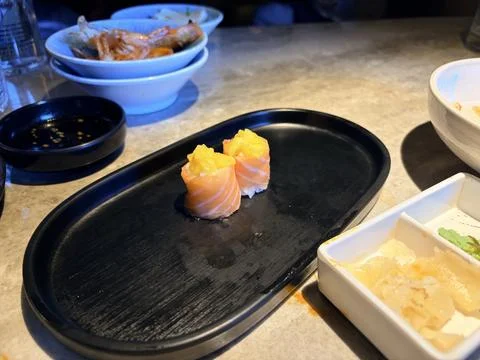 Salmon Sushi Rolls with Mango on Black Plate in Japanese Restaurant Stock-Fotos