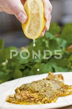 Salmon trout with a herb crust being drizzled with lemon juice Stock Photos