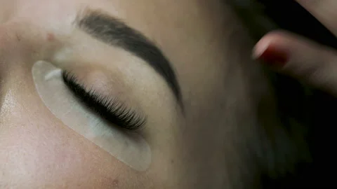 Salon master removing the white tape on flawless client's face after eyelashes  Видео 106985211
