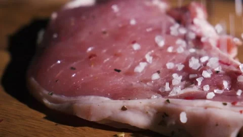 Salt and spices close-up sips on a piece of fresh raw beef meat Stock Footage 130786960