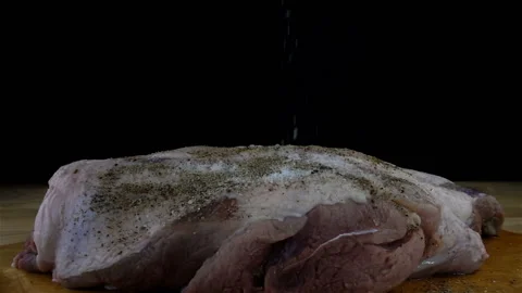 Salt and spices fall on a raw piece of meat in slow motion. Stock Footage 154179188
