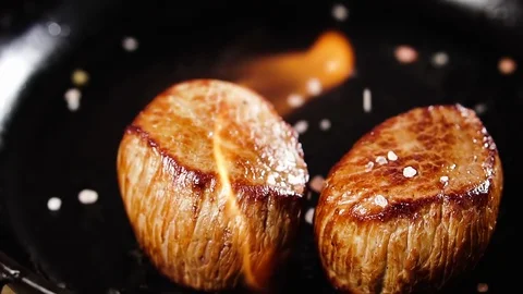 Salt and spices fall on two steaks filet mignon in a pan with flame, slow mot Stock Footage 126221586