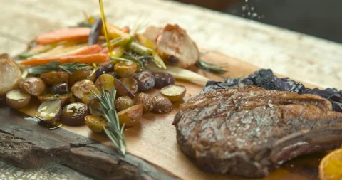 Salt being sprinkled on roasted rack of pork, with thyme, roasted potatoes, onio Stock Footage 199458719