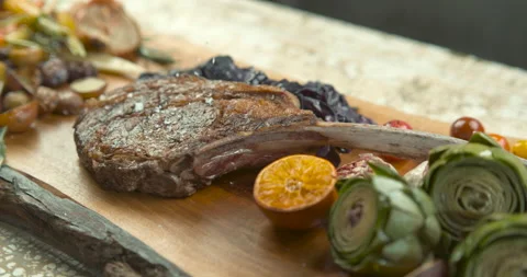 Salt being sprinkled on roasted rack of pork, with thyme, roasted potatoes, onio Stock Footage 199459244