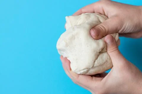 Salt dough for modeling in the hands of a child on a blue background Stock Photos