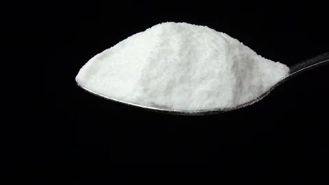 Salt falling from the iron spoon, black background studio, slow motion Vidéo 74725891