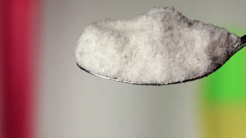 Salt falling from the iron spoon. Blurred background. Slow motion Stock Footage 75523396