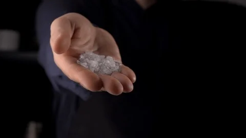 Salt falling from man's hand on dark background Video stock 115084462