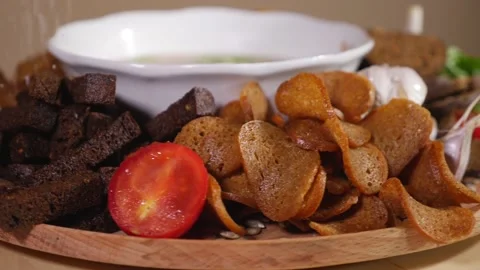 Salt falling on a plate with soup, bread crackers and fresh vegetables Stock Footage 124384034
