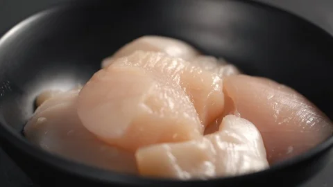 Salt falls down in slow motion to the spinning bowl with raw chicken brests Stock Footage 127430405