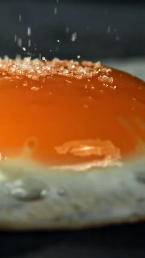 Salt falls on the fried egg. Filmed on a high-speed camera at 1000 fps Stock Footage 335371064