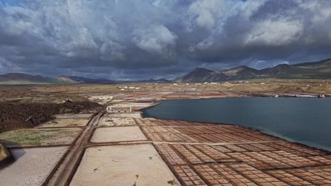 Salt fields in Lanzarote, Spain with plant life and mountains Stock Footage 331798455