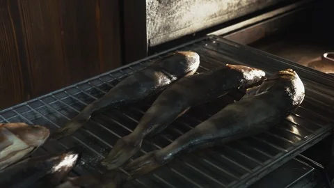 Salt fish lying on grill or grate placed in smokehouse or smoke oven for smoking Stock Footage 94592107