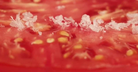 Salt flakes falling onto a beef tomato closeup Stock Footage 205300673