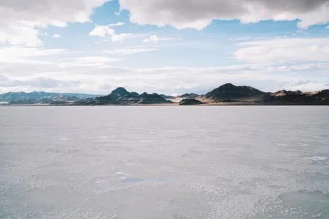 Salt flat with mountains under cloudy sky landscape Stock Photos