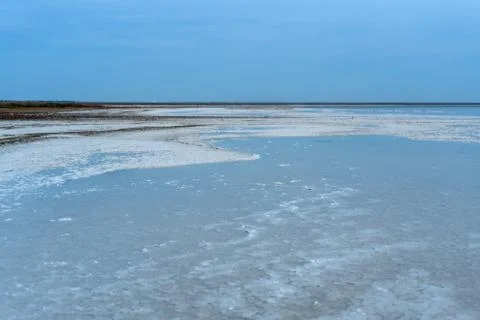 Salt lake. Clouds on a background of red water Salt lake. Wooden poles, sand. Stock Photos