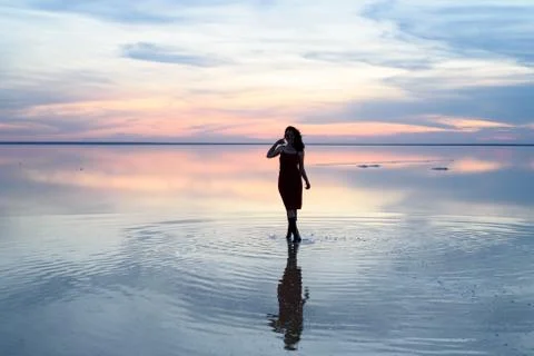 Salt lake. Girl standing in the water at sunset. Stock Photos