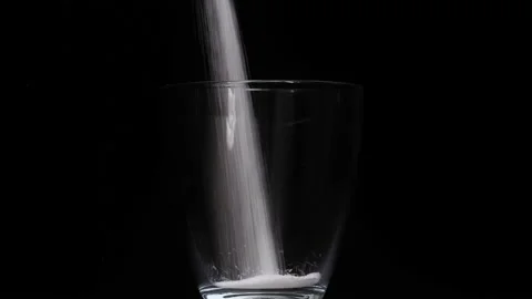 Salt is poured into a black glass on a black background Stock Footage