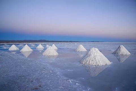 Salt pyramids in a reflective salt flat at sunset Stock Photos