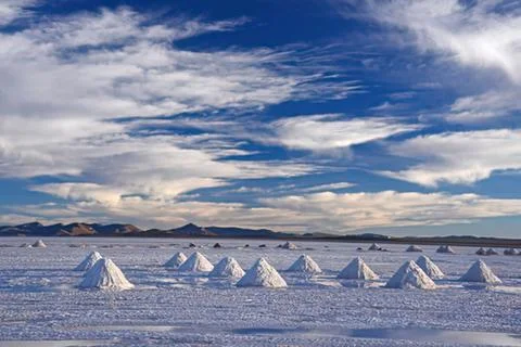 Salt pyramids in a vast salt flat under clouds Stock Photos