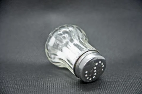 Salt shaker made of glass against a black background Stock Photos